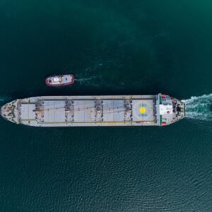 Aerial view of tug boat assisting big bulk carrier cargo ship. Large ship escorted by tugboat.